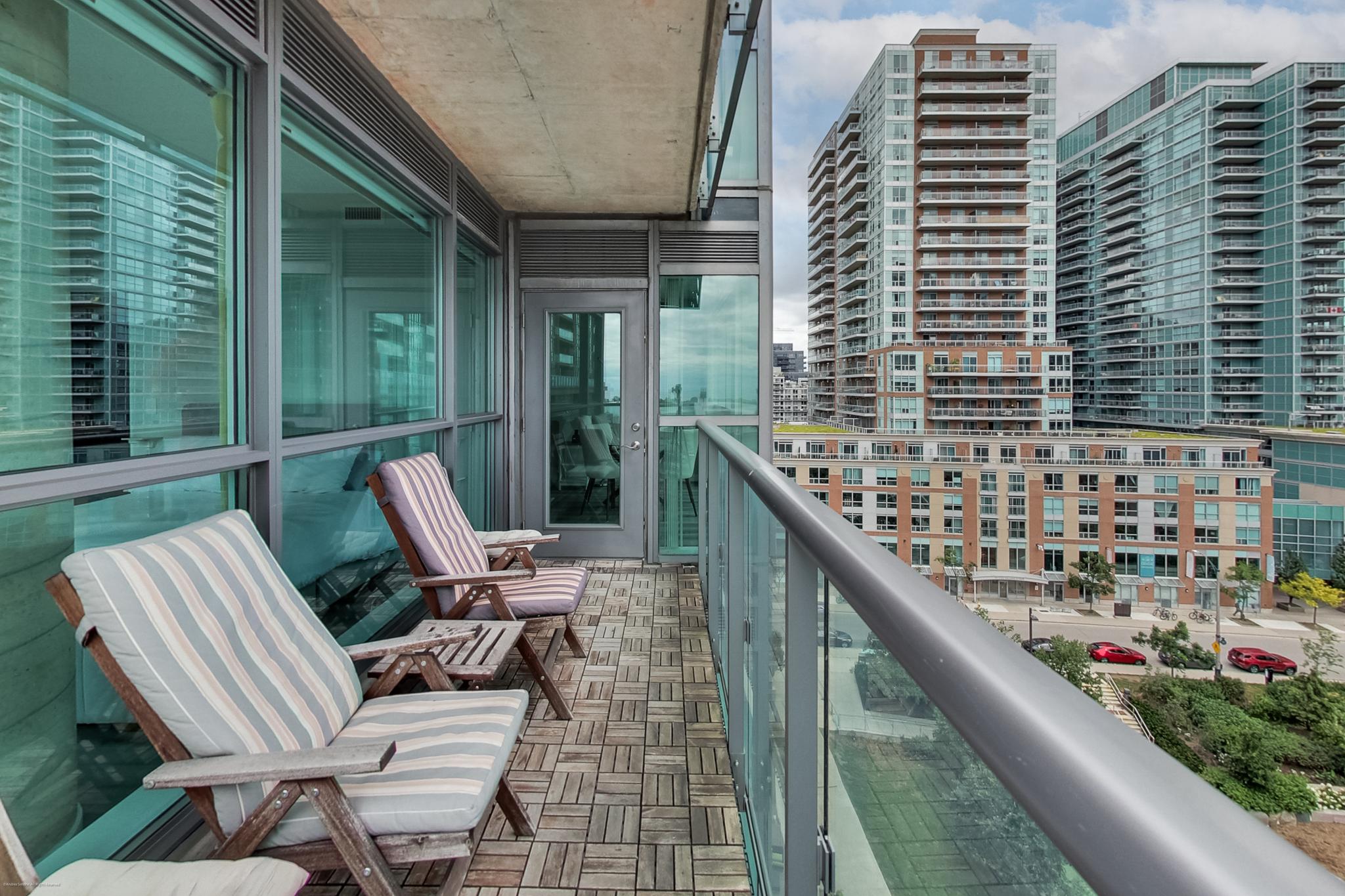 21 | Liberty Village Toronto | Your Online Neighbourhood Guide Balcony with striped lounge chairs overlooking a city skyline of modern glass apartment buildings.