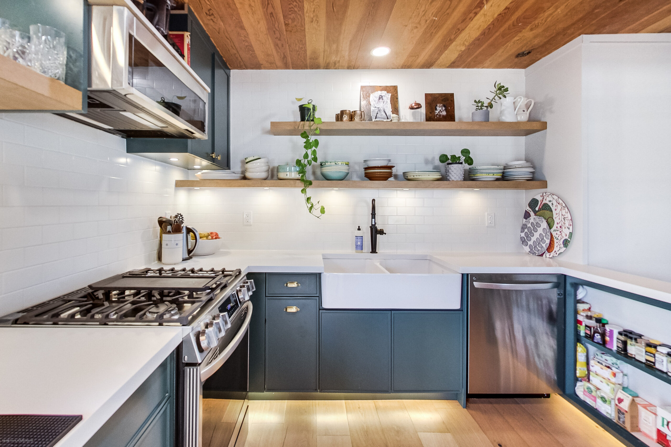 andreasimonecom | Liberty Village Toronto | Your Online Neighbourhood Guide Modern kitchen with navy cabinets, white countertops, and open wood shelves holding bowls and plants.